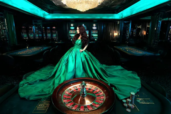 A woman in a luxurious green gown next to an ornate roulette wheel, capturing the upscale casino mood of AH99.